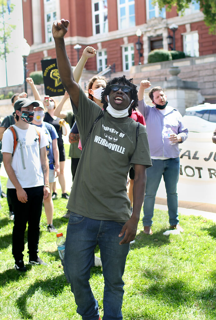 Protester Drew Falvey, center, from St. Louis raises his fist as the closing chant of the Expect Us demonstration